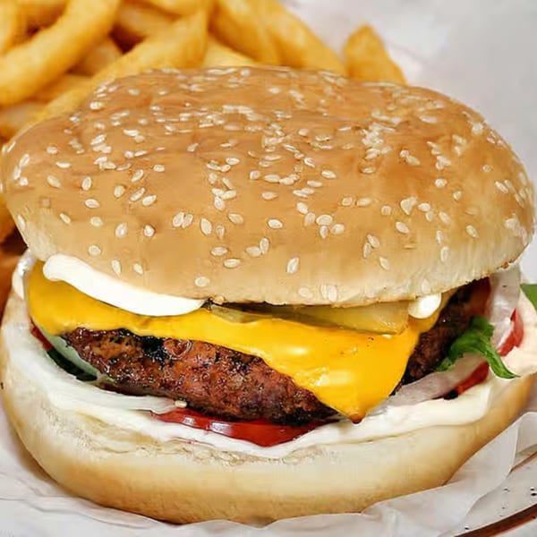 A cheeseburger with lettuce, tomato, onion, and mayonnaise, served with a side of fries.